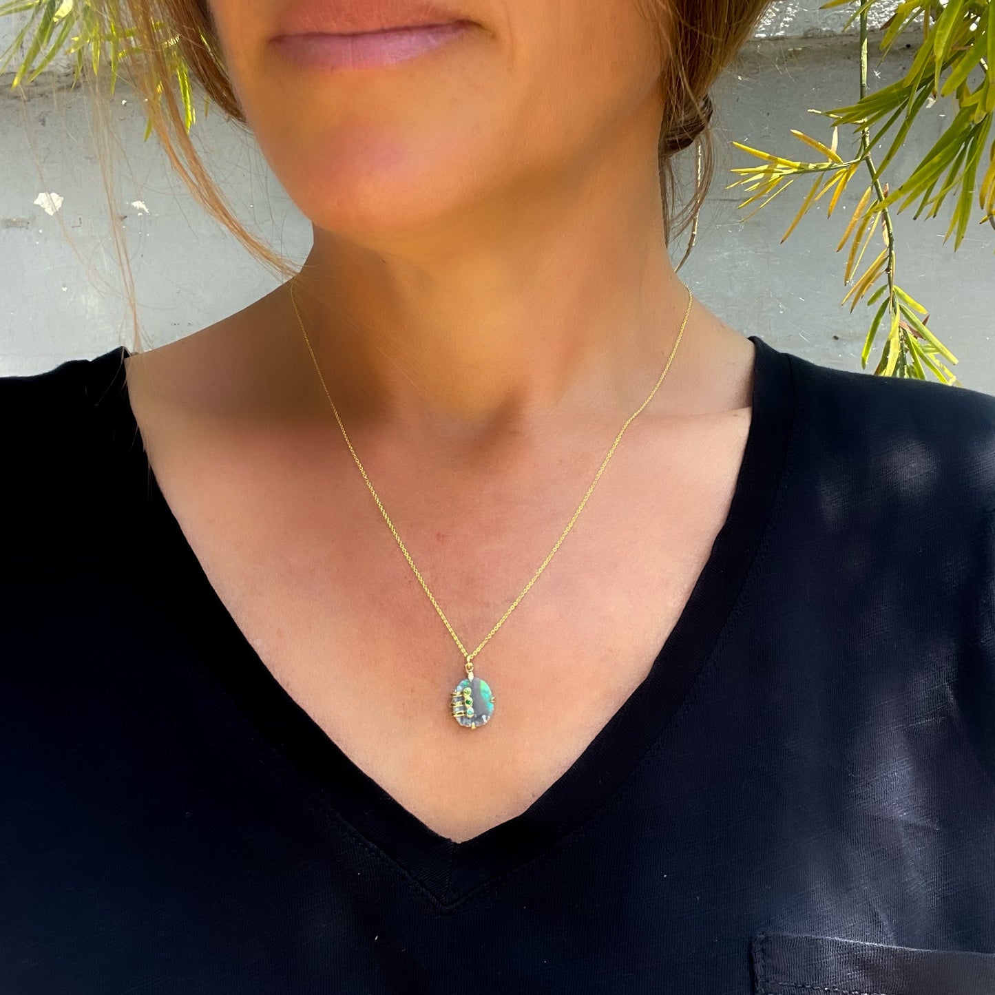Model wearing an Australian Opal Necklace by NIXIN Jewelry for scale. The opal jewelry is a Black Opal Necklace.