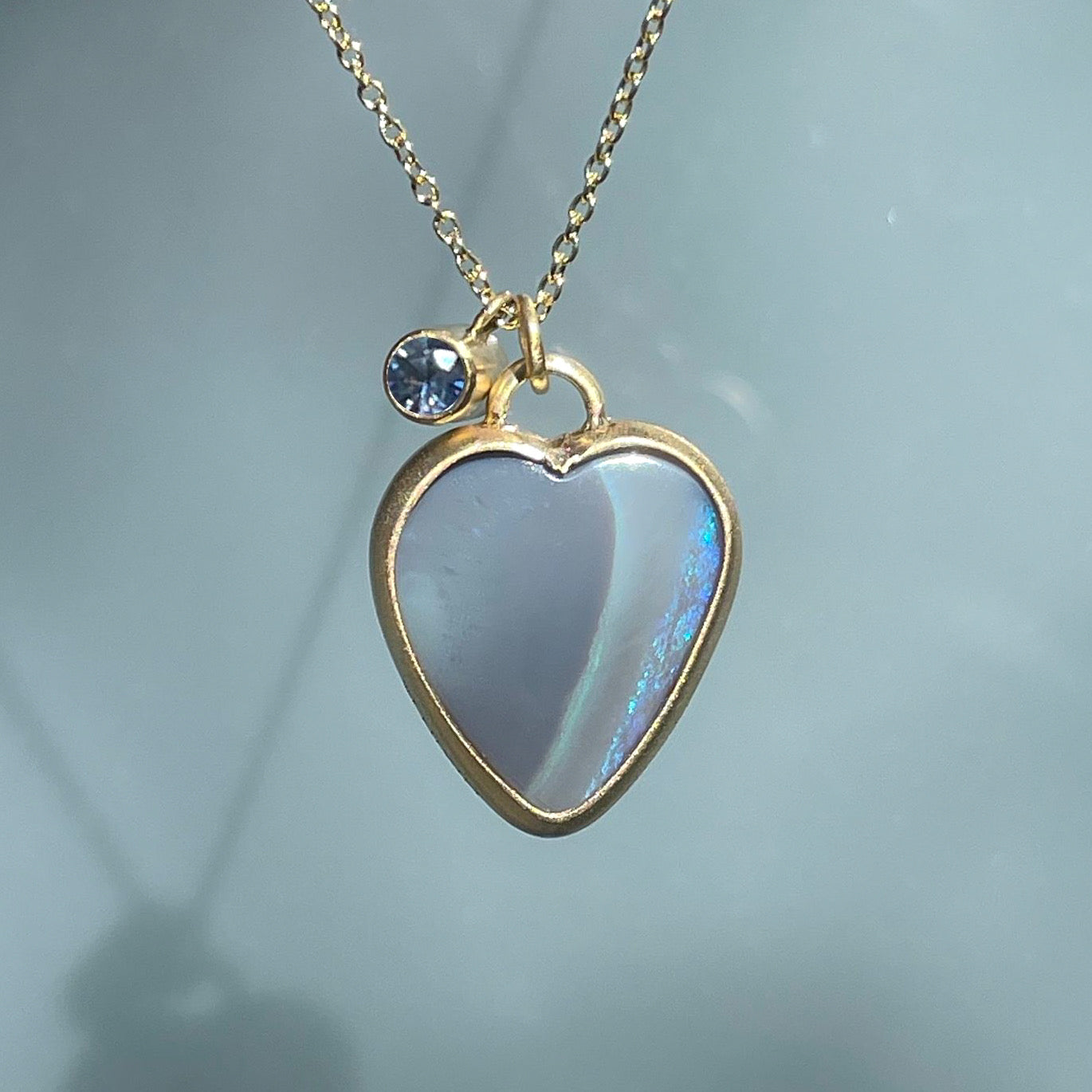 A two sided Australian Opal Necklace by NIXIN Jewelry with a semi black opal and blue sapphire set in 14k gold.