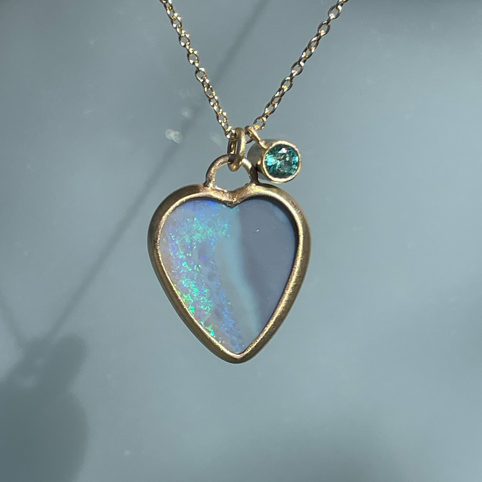 An Australian Opal Necklace by NIXIN Jewelry with a two sided opal and an emerald charm.
