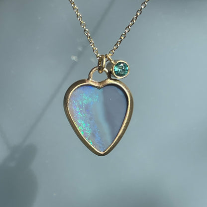 An Australian Opal Necklace by NIXIN Jewelry with a two sided opal and an emerald charm.
