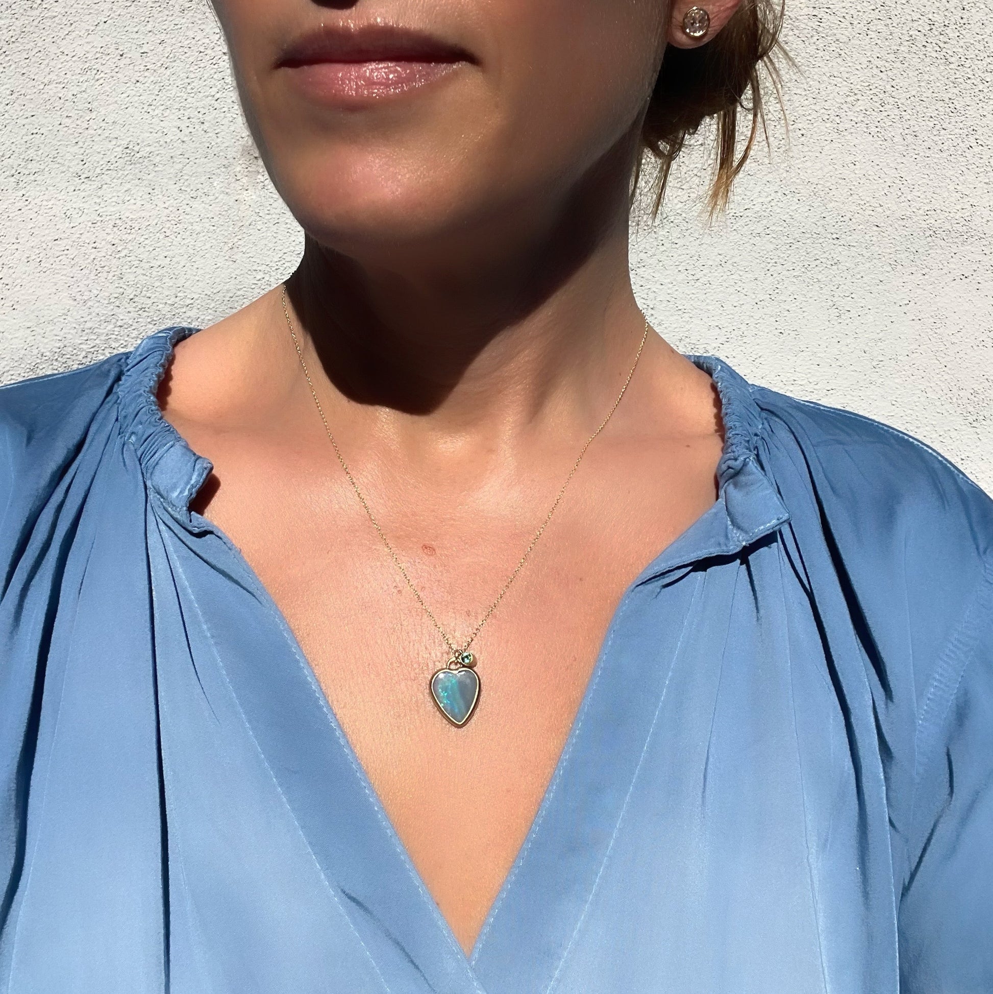 Model wearing an Australian Opal Necklace with an opal heart pendant and emerald charm.