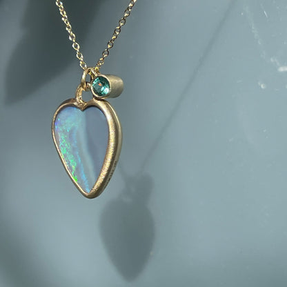 Side view of an Australian Opal Necklace by NIXIN Jewelry with an opal heart and emerald charm.