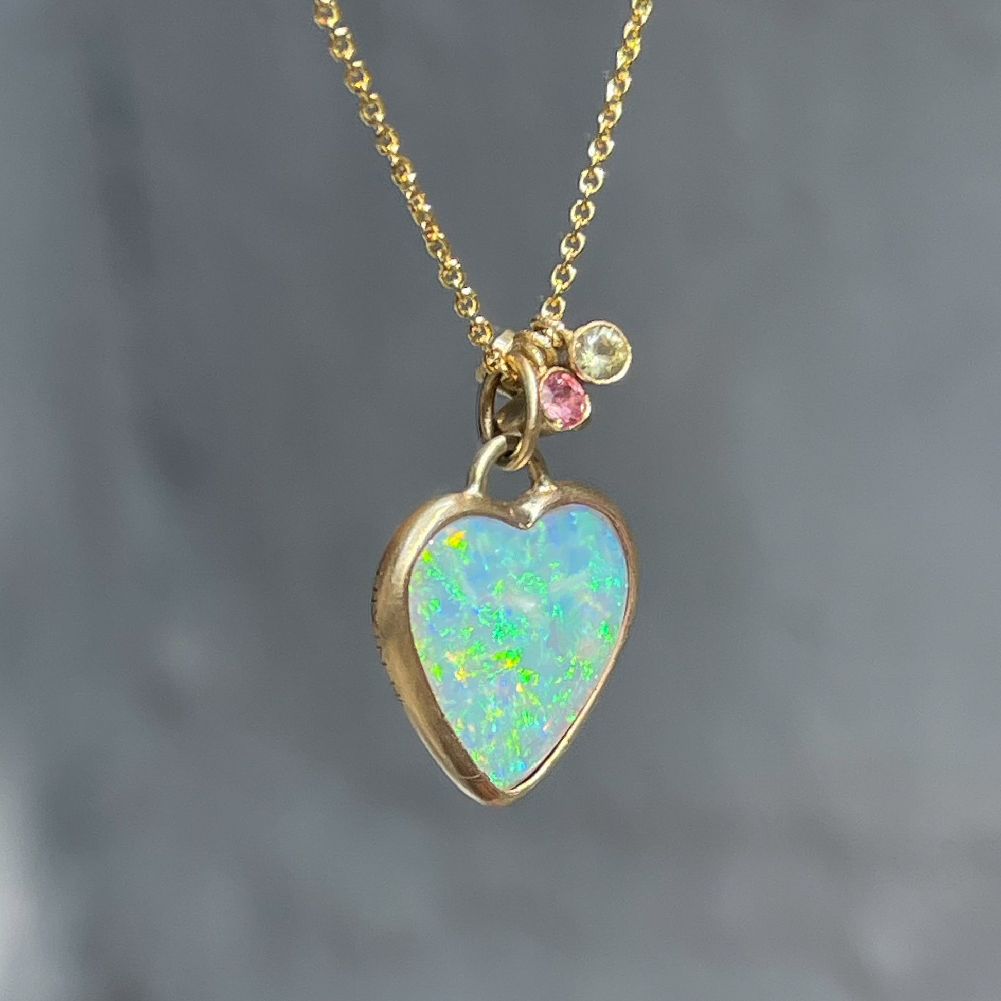 An Australian Opal Necklace by NIXIN Jewelry. The heart pendant necklace has sapphire and emerald charms.