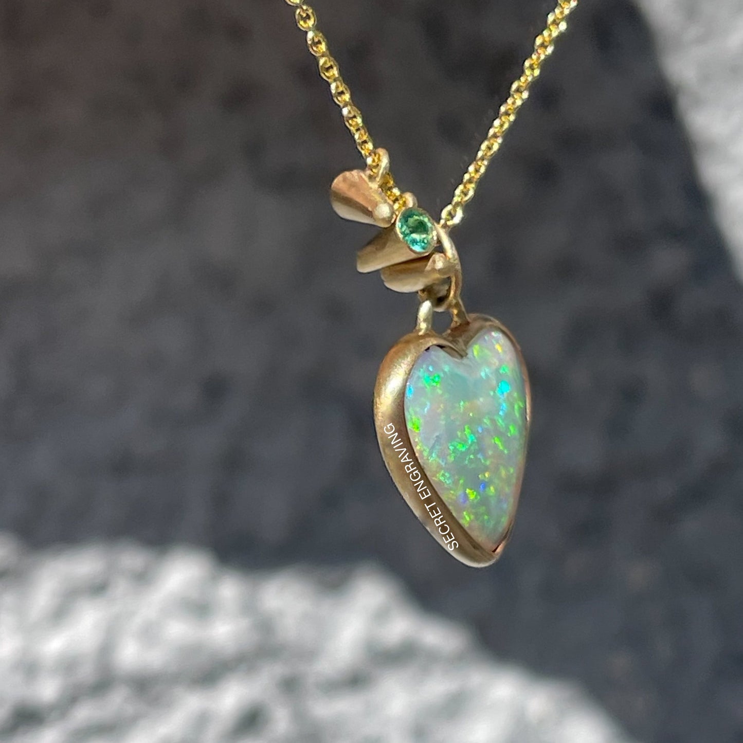 Side view of an Australian Opal Necklace by NIXIN Jewelry showing the 14k gold bezel setting of the heart opal and the location of the secret engraving.