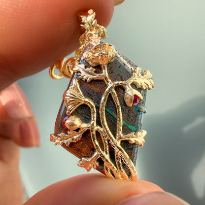 An Australian Opal Necklace by NIXIN Jewelry is shown held between fingers to provide a clear sense of scale and the intricate texture of the matte gold poppy petals. This close-up view reveals the unique fine jewelry craftsmanship, including the delicate prong setting and a whisper of the secret engraving. It serves as a stunning example of rare opal jewelry tailored for the high-end women's luxury necklace market.