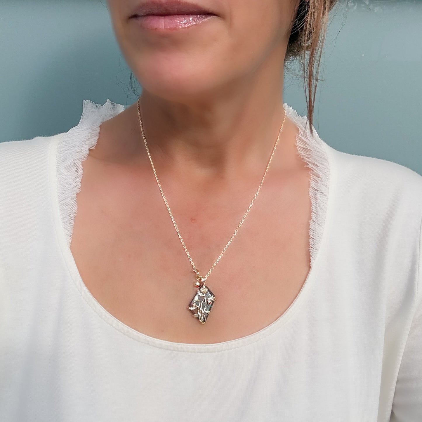 An Australian Opal Pendant by NIXIN Jewelry is shown worn on a model to illustrate how the luxury necklace sits elegantly against the neckline. The gold opal necklace provides a striking reversible design, making it a versatile piece of unique jewelry for both day and evening wear. This lifestyle image helps clients visualize the scale and presence of this rare opal necklace.