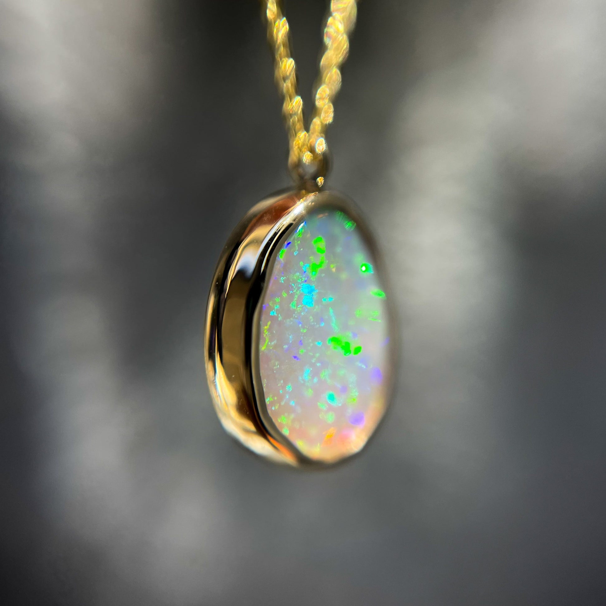 Close up of an Australian Opal Necklace by NIXIN Jewelry showing details of the gold bezel around the lightning ridge black opal.