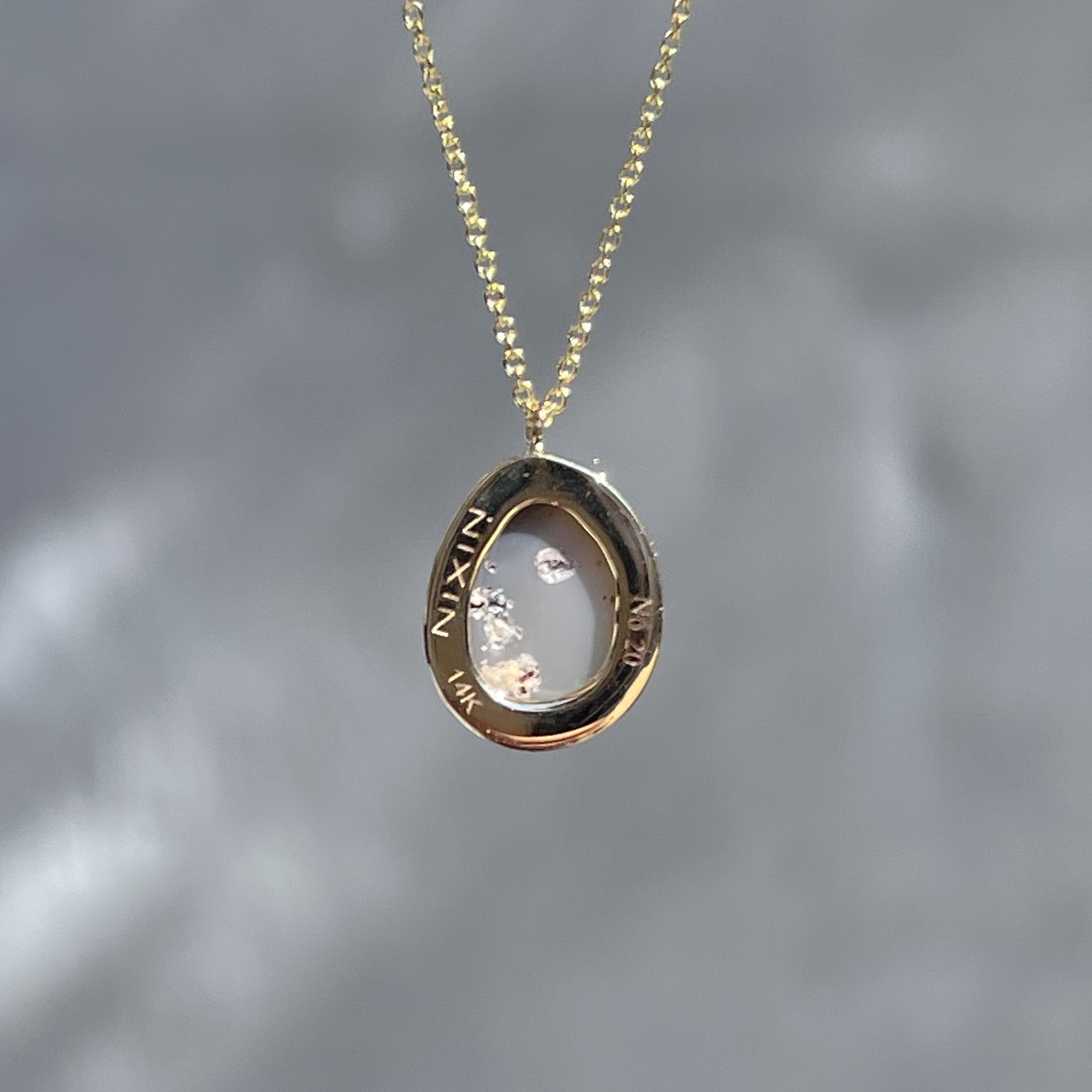 Back view of an Australian Opal Necklace by NIXIN Jewelry showing the real opal and the engraving on the bezel seat.