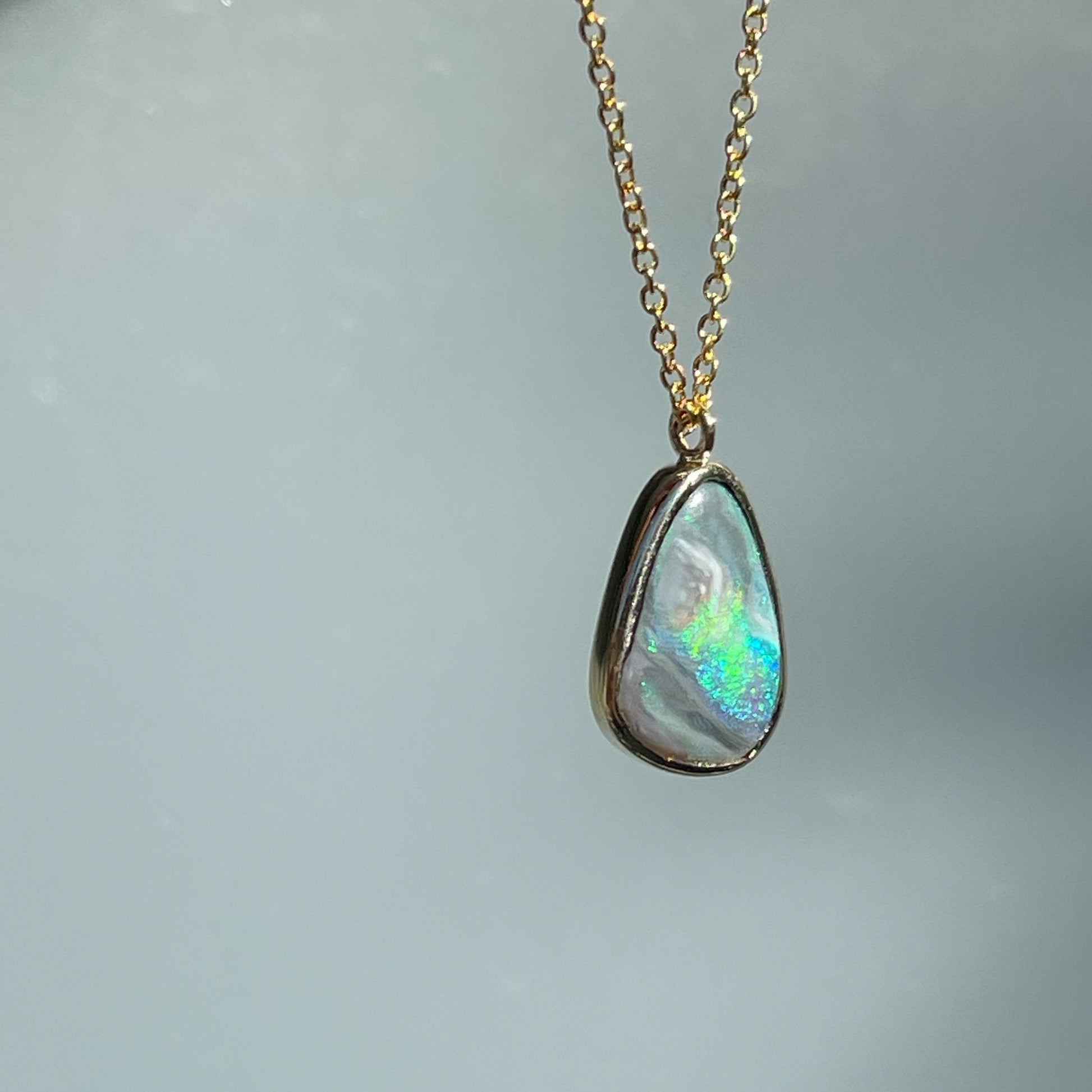 Angled view of an Australian Opal Necklace by NIXIN Jewelry showing the side of the bezel setting. The rare opal necklace is one of a kind.