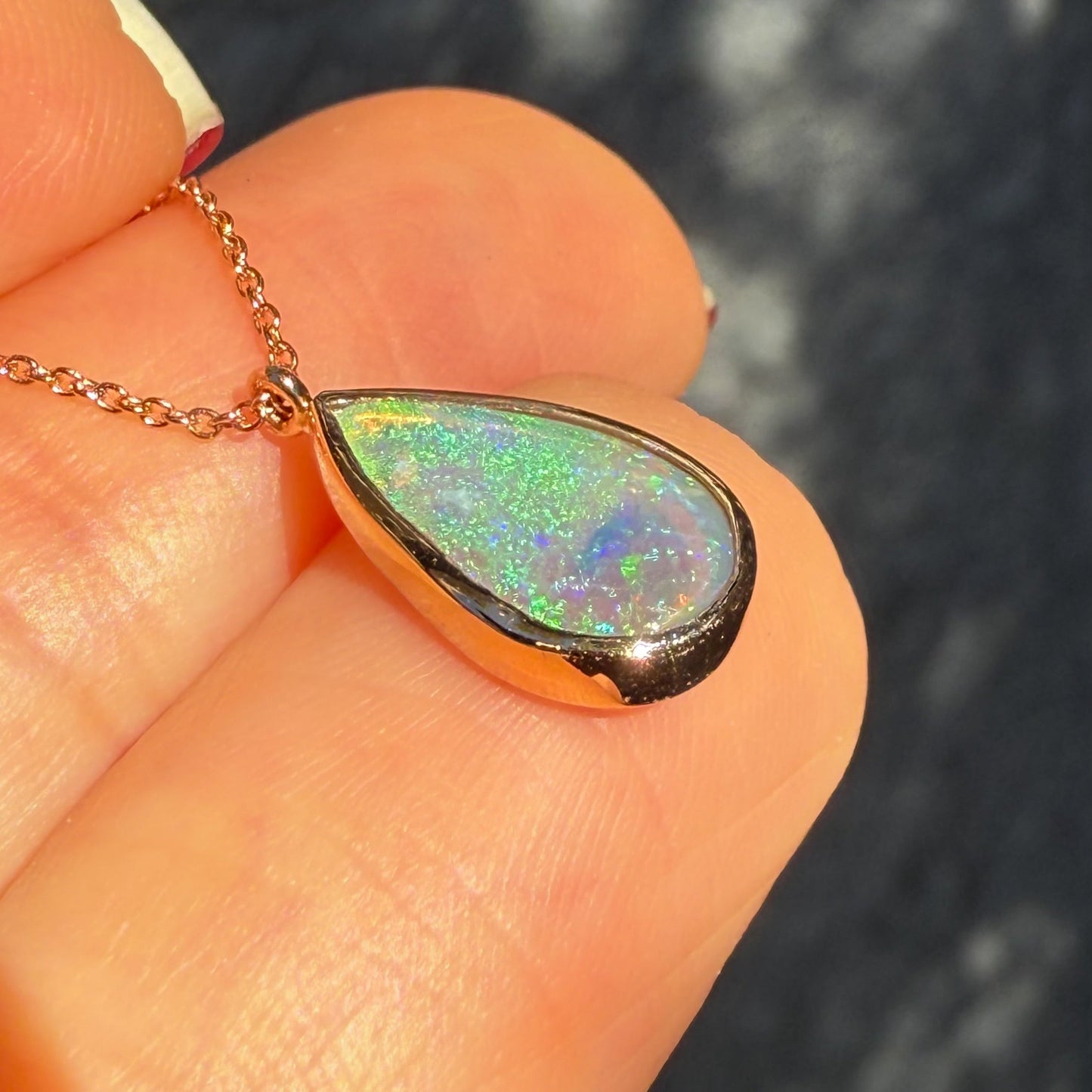 An Australian Opal Necklace by NIXIN Jewelry shown at a profile angle, highlighting the depth and thickness of the cabochon opal pendant. The detailed craftsmanship of the bezel setting and dimensionality of the natural opal attract are visible. This image shows the quality of the unique fine jewelry.