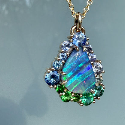 The elegant composition of an Australian Opal Necklace by NIXIN Jewelry features a teardrop-shaped boulder opal framed by a halo of gems. This luxury jewelry piece represents the best of Australian opal craftsmanship and unique fine jewelry.
