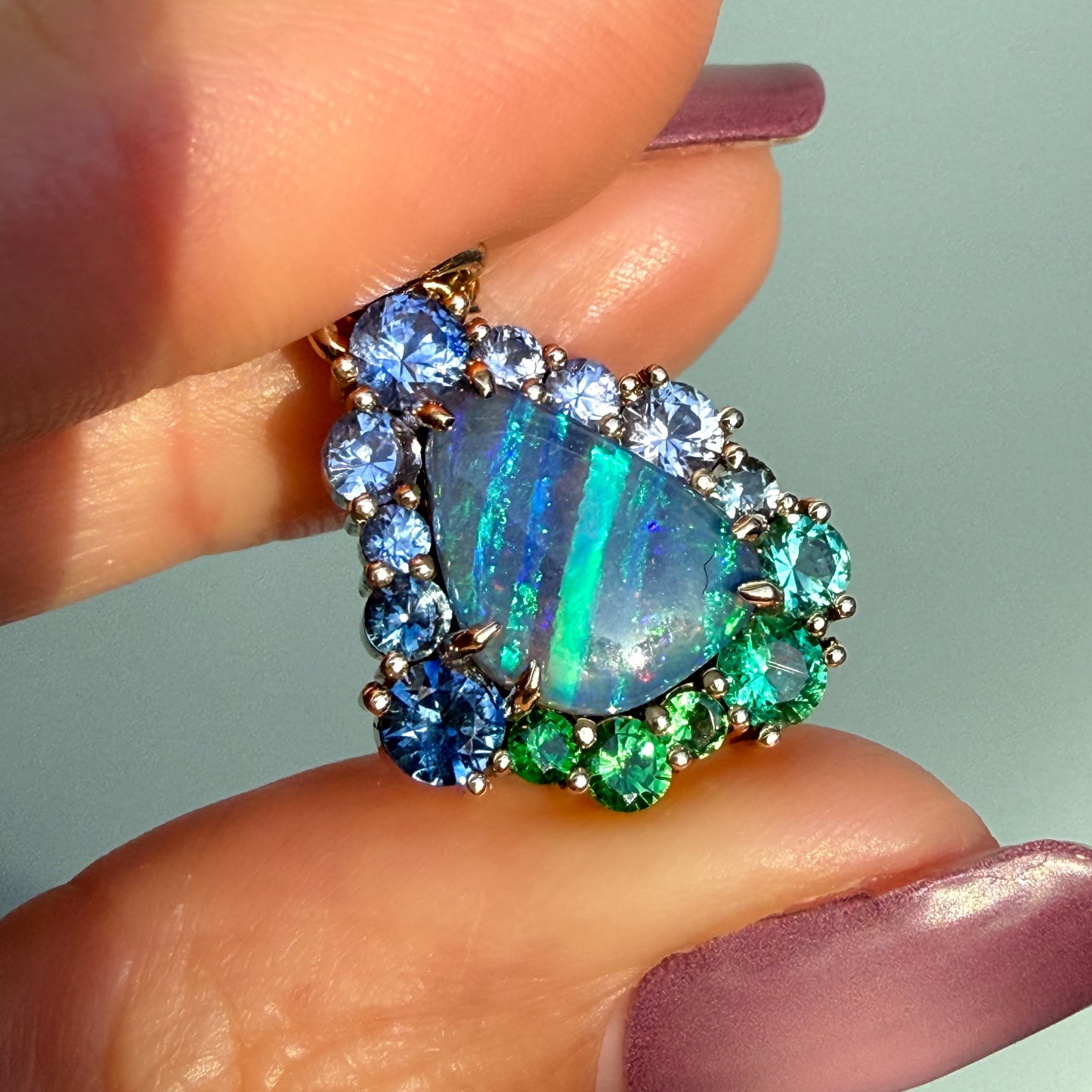 Held to show its scale, this Australian Opal Necklace by NIXIN Jewelry demonstrates the impressive flash of the natural opal stone. This rare opal necklace is an exquisite specimen of unique opal necklace design, making it a true work of art.