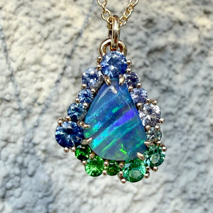 Photographed against a textured surface, this Australian Opal Necklace by NIXIN Jewelry highlights the organic beauty of a natural opal. The boulder opal necklace combines rare jewelry elements with contemporary sapphire jewelry for a modern luxury look.