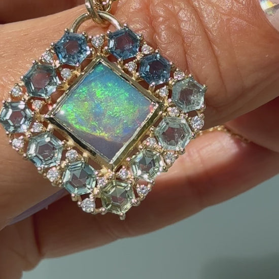 A video demonstration highlights the dynamic color shifts of an Australian Opal Pendant by NIXIN Jewelry as it moves through the light. The luxury black opal necklace features a rare lightning ridge opal in a gold bezel setting, bordered by an ombre halo of hexagon-cut montana sapphires and prong-set diamonds. The footage also turns to capture the reverse side, showcasing a structural honeycomb latticework that elevates this piece of unique fine jewelry into a work of wearable jewelry art.