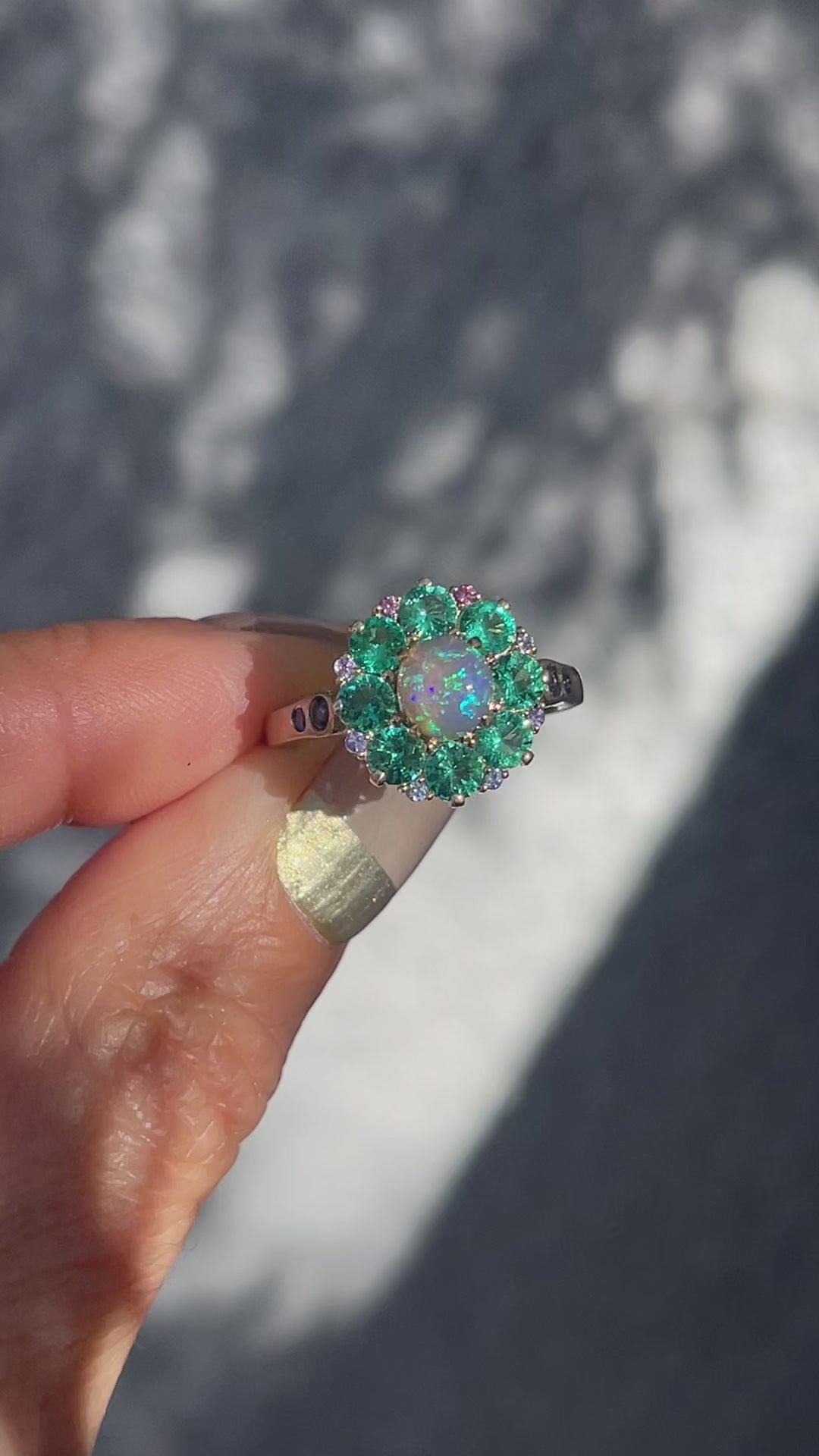 Video of an Australian Opal Ring by NIXIN Jewelry. Shows the emerald and opal ring flashing in the sun.