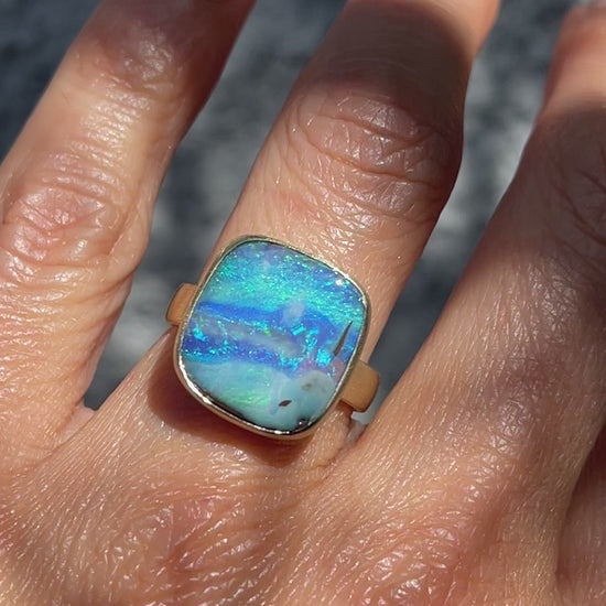 An Australian Opal Ring by NIXIN Jewelry modeled on a hand. The boulder opal ring is an example of jewelry art.