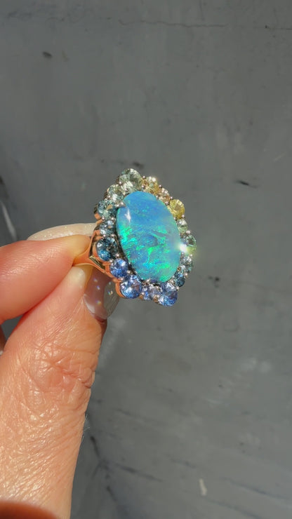 An Australian Opal Ring by NIXIN Jewelry. This video showcases the brilliant play-of-color in a rare black opal and the sparkle of its ombré sapphire halo. The lightning ridge opal is set in a gold ring, highlighting the movement of this luxury jewelry.