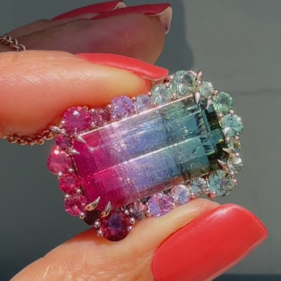 Video of the Empress Imbued Tourmaline Necklace by NIXIN Jewelry turning in hand against a sunlit window, revealing color-shifting facets of the tourmaline and sapphires from every angle.