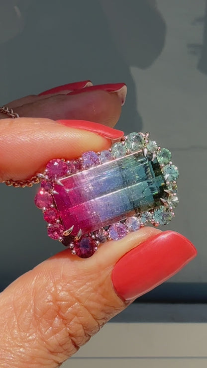 Video of the Empress Imbued Tourmaline Necklace by NIXIN Jewelry turning in hand against a sunlit window, revealing color-shifting facets of the tourmaline and sapphires from every angle.