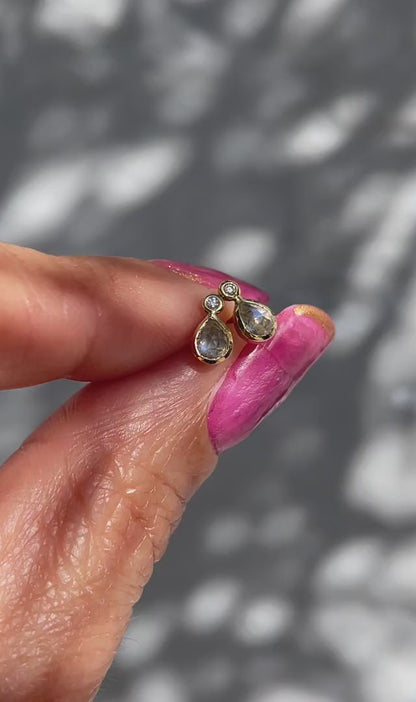 A video of Moonstone Earrings by NIXIN Jewelry held in the sunlight. The dainty studs are made with blue moonstone and tiny diamonds.