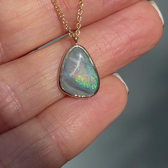 Video of an Australian Opal Necklace by NIXIN Jewelry moving in the sunlight. The Black opal necklace is set in gold.