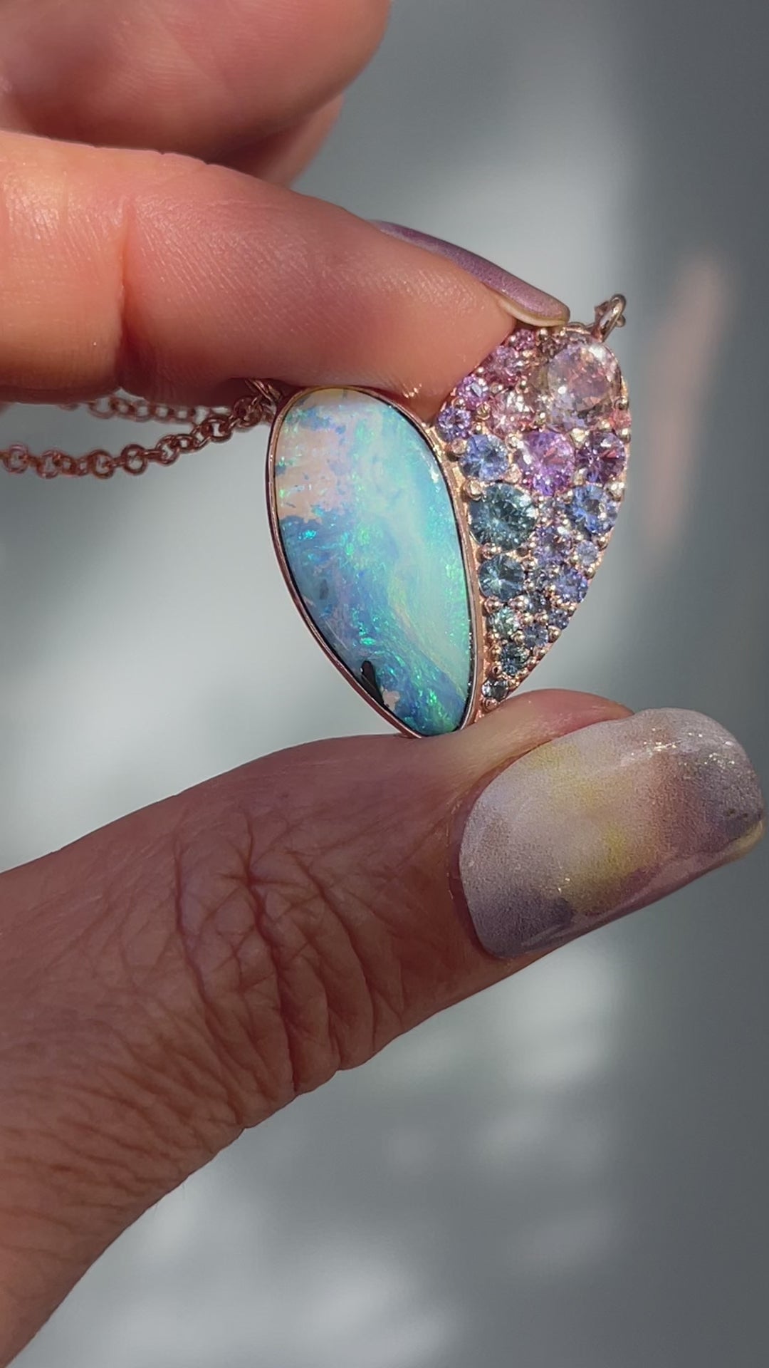 Video of a Heart Opal Necklace by NIXIN Jewelry with a Boulder Opal and sapphires set in rose gold.