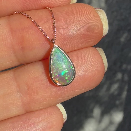 An Australian Opal Necklace by NIXIN Jewelry displayed in motion to showcase the dynamic spectral shift of this unique opal jewelry. The video captures the vibrant green, blue, and red fire flashing across the crystal opal necklace as it moves; this luxury necklace is a true piece of jewelry art. Essential viewing for buyers searching for a rose gold opal necklace with the highest quality rare opal jewelry movement and color.