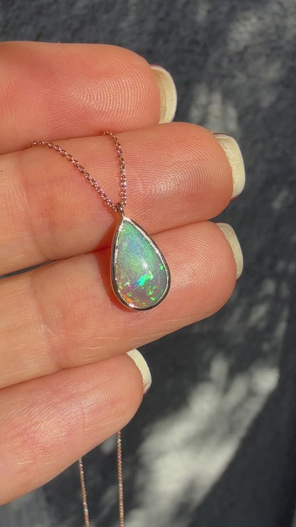 An Australian Opal Necklace by NIXIN Jewelry displayed in motion to showcase the dynamic spectral shift of this unique opal jewelry. The video captures the vibrant green, blue, and red fire flashing across the crystal opal necklace as it moves; this luxury necklace is a true piece of jewelry art. Essential viewing for buyers searching for a rose gold opal necklace with the highest quality rare opal jewelry movement and color.