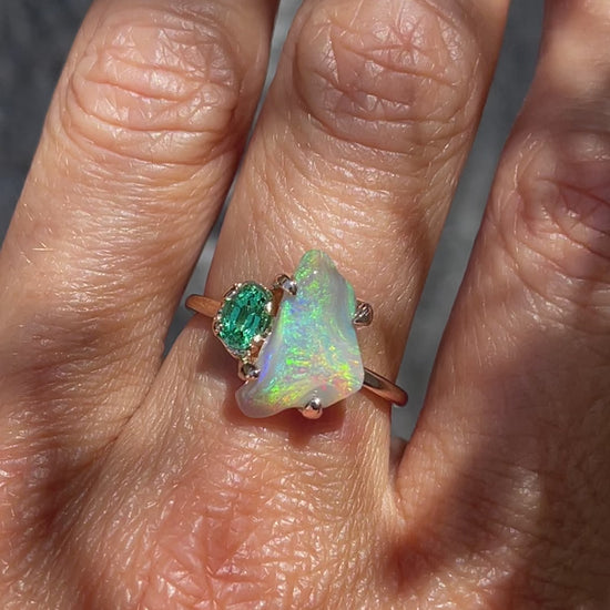 Video of an Opal and Emerald Ring by NIXIN Jewelry modeled on a hand. The Black Opal ring is made in rose gold with a vibrant green emerald.