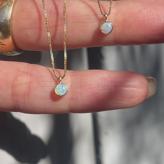 A video of two Australian Opal Necklaces by NIXIN Jewelry held in sunlight. The Opal Pendants hang from delicate 14k gold chains.