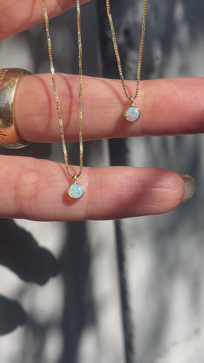 A video of two Australian Opal Necklaces by NIXIN Jewelry held in sunlight. The Opal Pendants hang from delicate 14k gold chains.