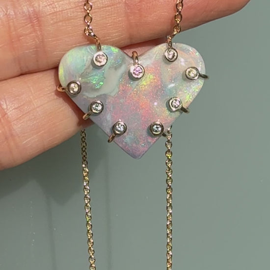 An Australian Opal Necklace by NIXIN Jewelry video demonstrating the intense opal fire in the semi black opal heart pendant. The movement highlights the unique light diffraction and the security of the sapphires in the prong setting. This rare opal jewelry video is a true display of jewelry art.