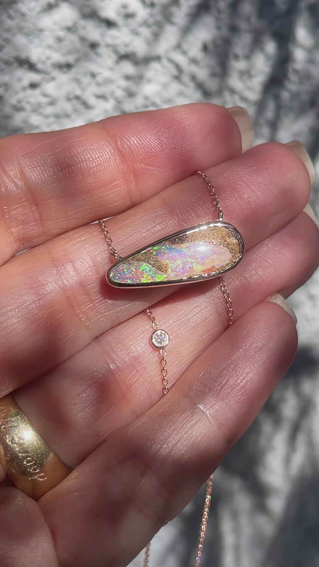 Video of an Australian Opal Necklace by NIXIN Jewelry moving in the sunlight. The rose gold opal necklace has a bezel set opal and a small diamond in the chain.