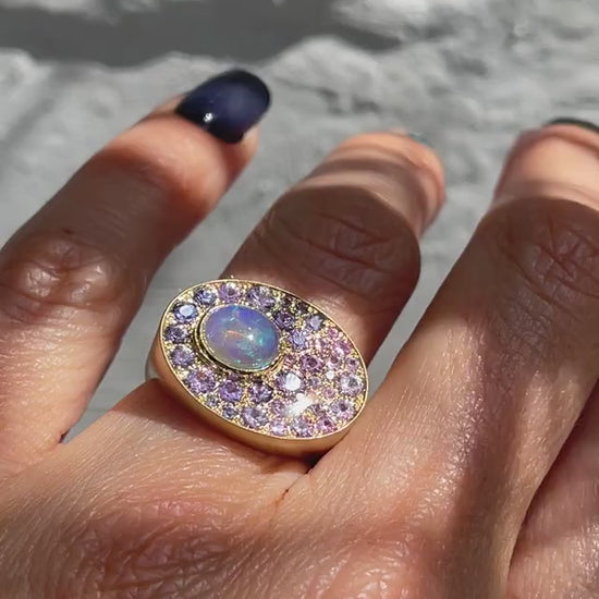 A video of an Australian Opal Ring by NIXIN Jewelry modeled on the hand. The sapphire and opal ring is 14k yellow gold with a Crystal Opal and purple sapphires.