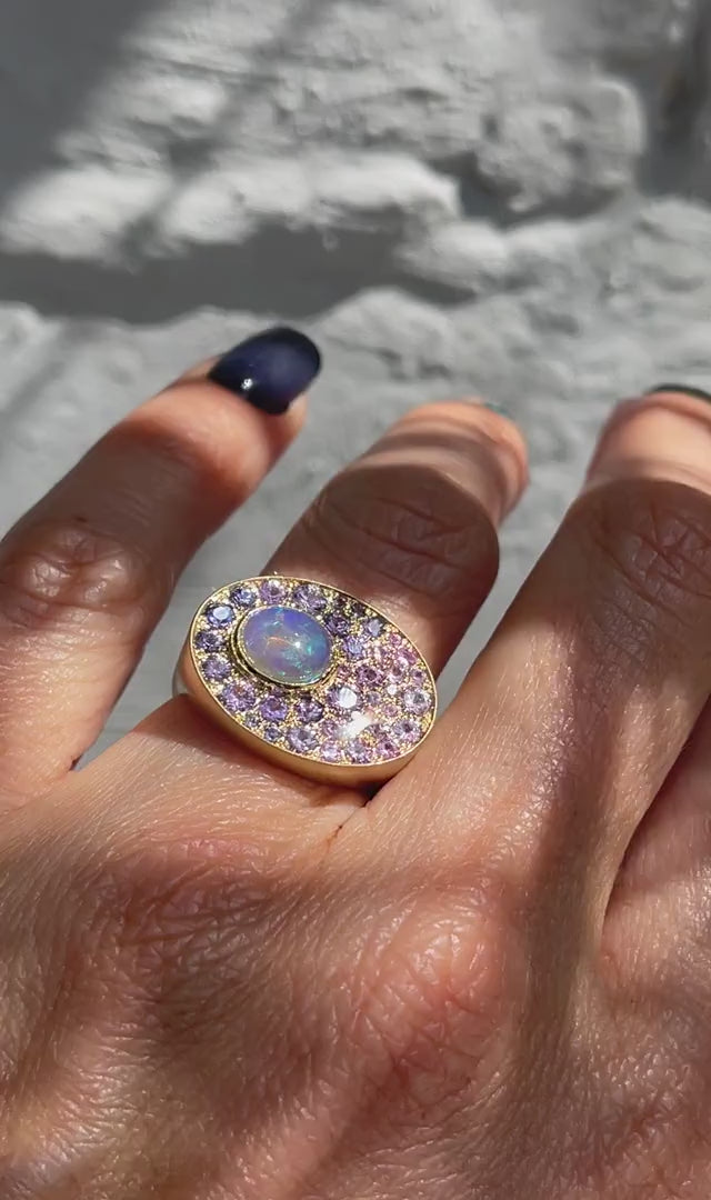 A video of an Australian Opal Ring by NIXIN Jewelry modeled on the hand. The sapphire and opal ring is 14k yellow gold with a Crystal Opal and purple sapphires.