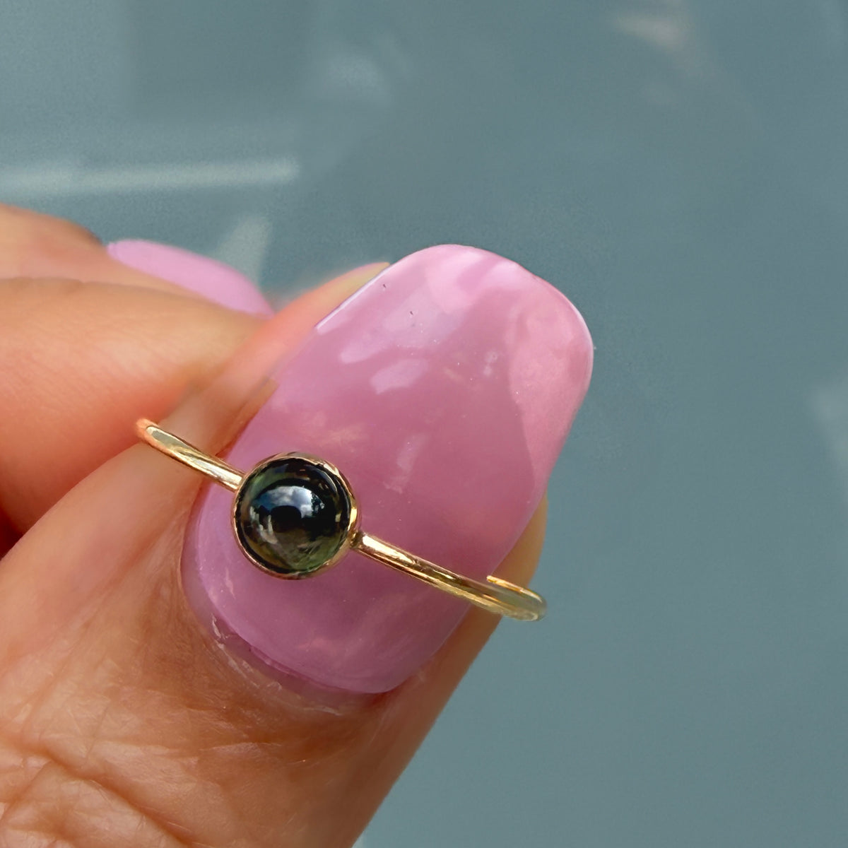 Lucky Green Tourmaline Ring in deep forest green, a single domed tourmaline cabochon bezel set in 14k gold on a fingertip.