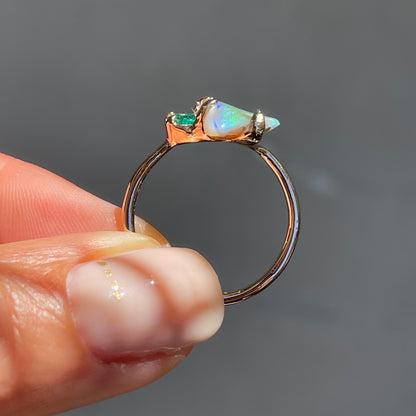 An Opal and Emerald Ring by NIXIN Jewelry shown in profile. The opal and emerald are both secured by claw prongs in this rose gold opal ring.