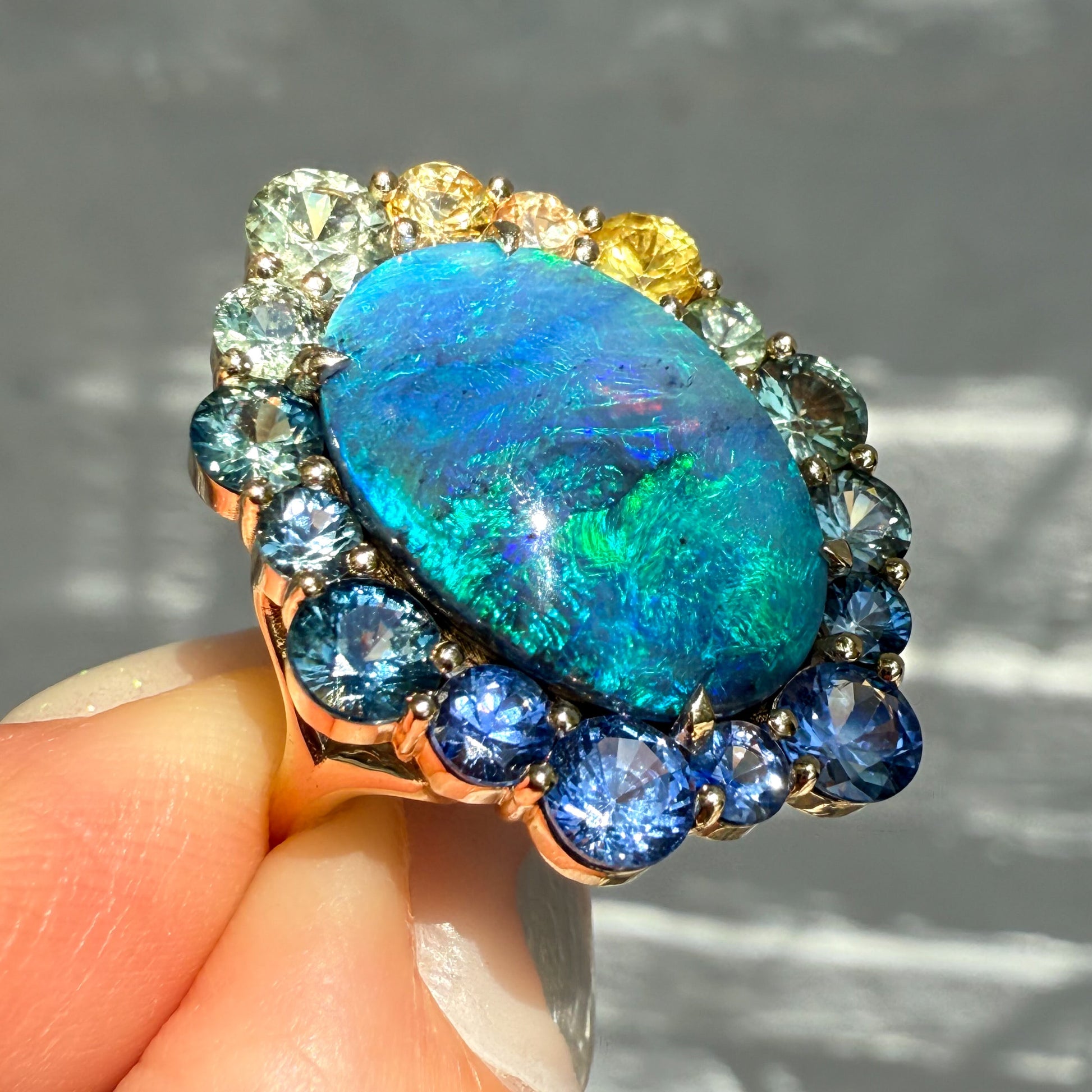 Side view of an Australian Opal Ring by NIXIN Jewelry. This sapphire opal ring is a stunning example of fine jewelry. It is an ideal women's luxury ring for a collector of rare Australian opal.