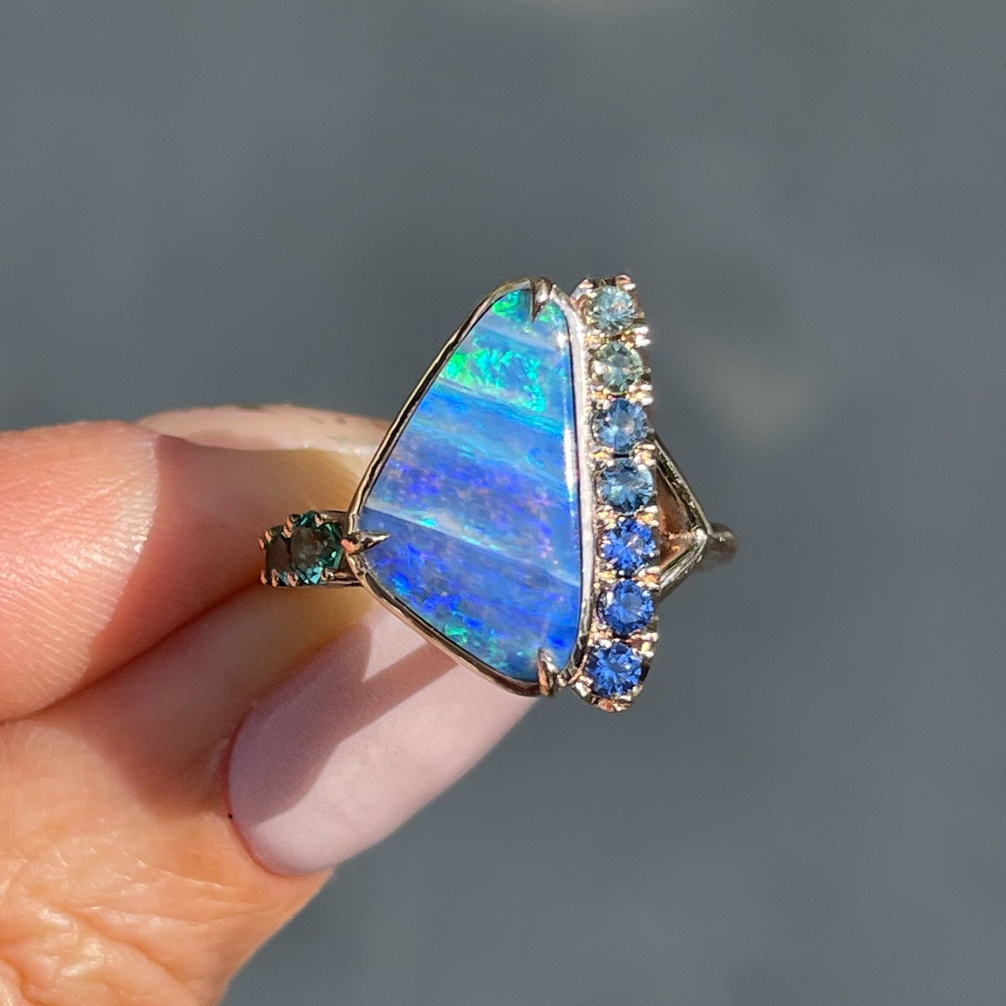 An Australian Opal Ring by NIXIN Jewelry with the opal and emeralds in prong setting.