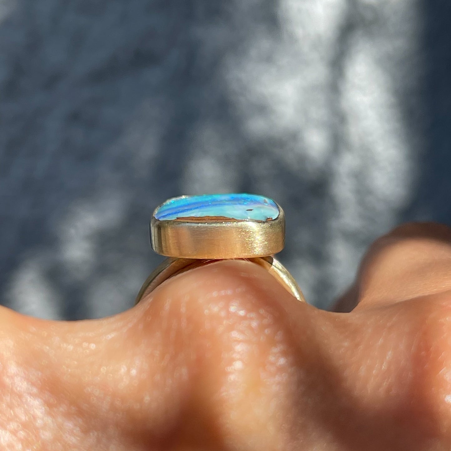 Profile shot of An Australian Opal Ring by NIXIN Jewelry worn on the hand. The blue opal ring is low profile.