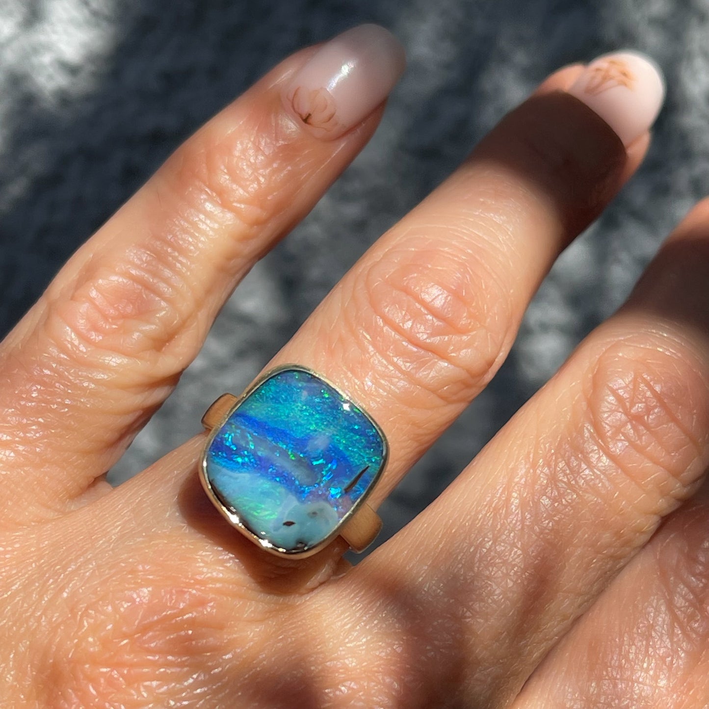 An Australian Opal Ring by NIXIN Jewelry modeled on a hand. Rare opal jewelry set in 14k gold.