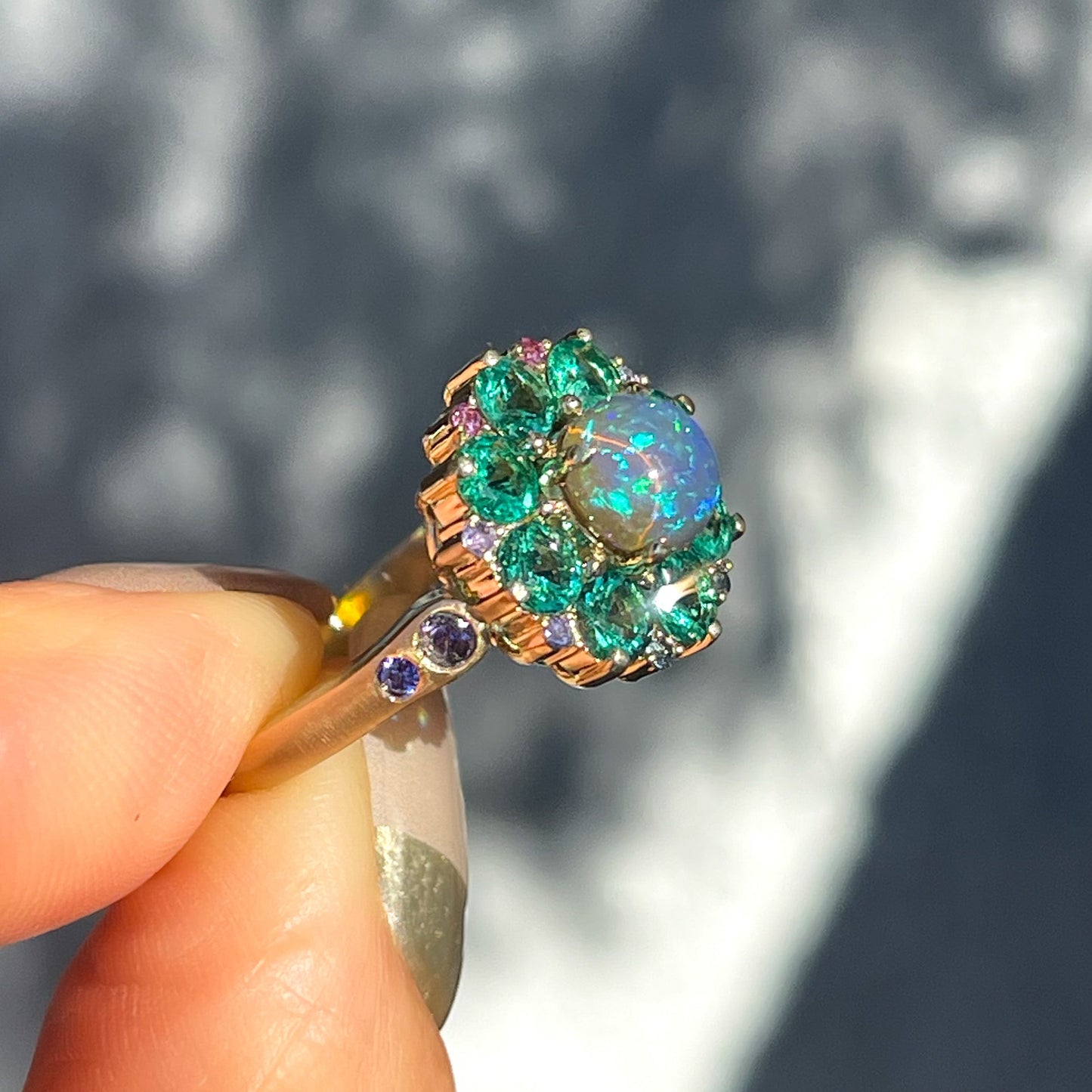 Side view of an Australian Opal Ring by NIXIN Jewelry. The emerald and opal ring has purple sapphires.