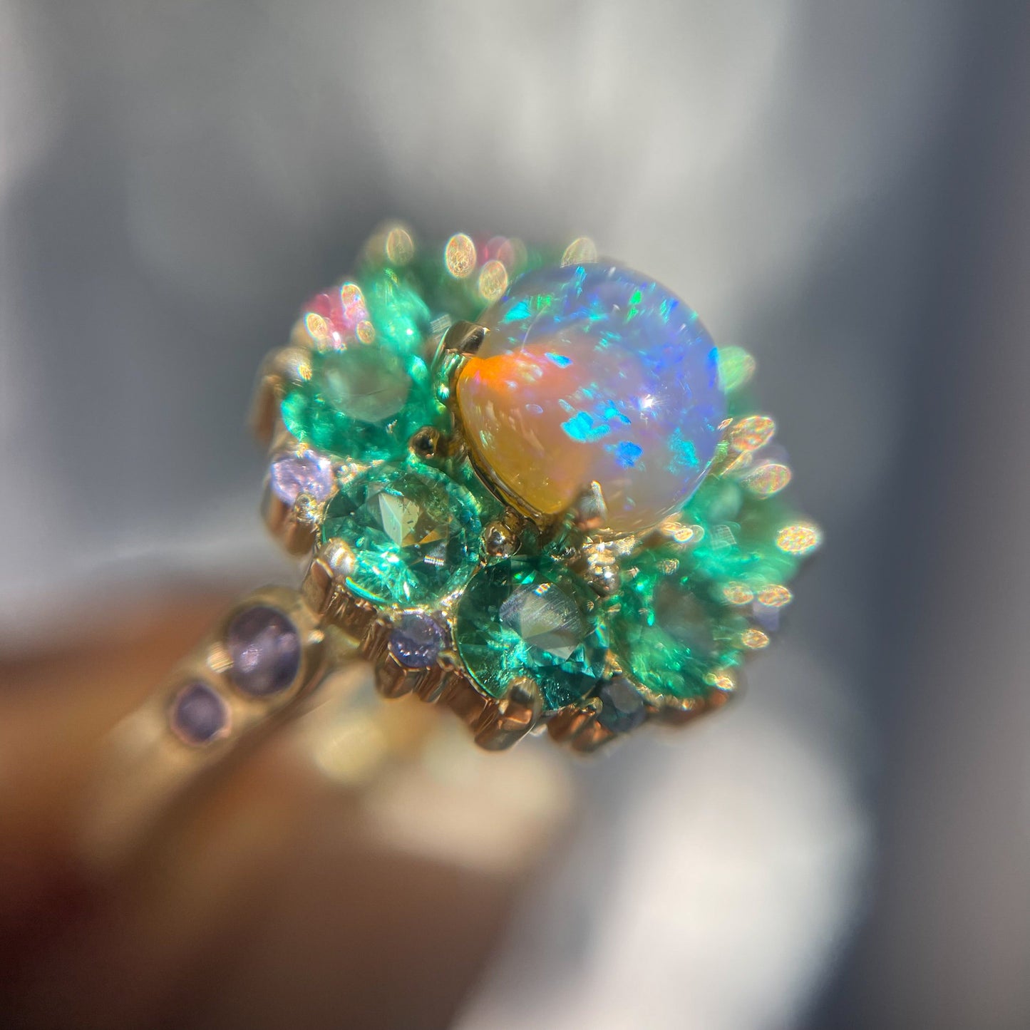 Magnified view of an Australian Opal Ring by NIXIN Jewelry showing the Black Opal and emeralds in the unique opal ring.