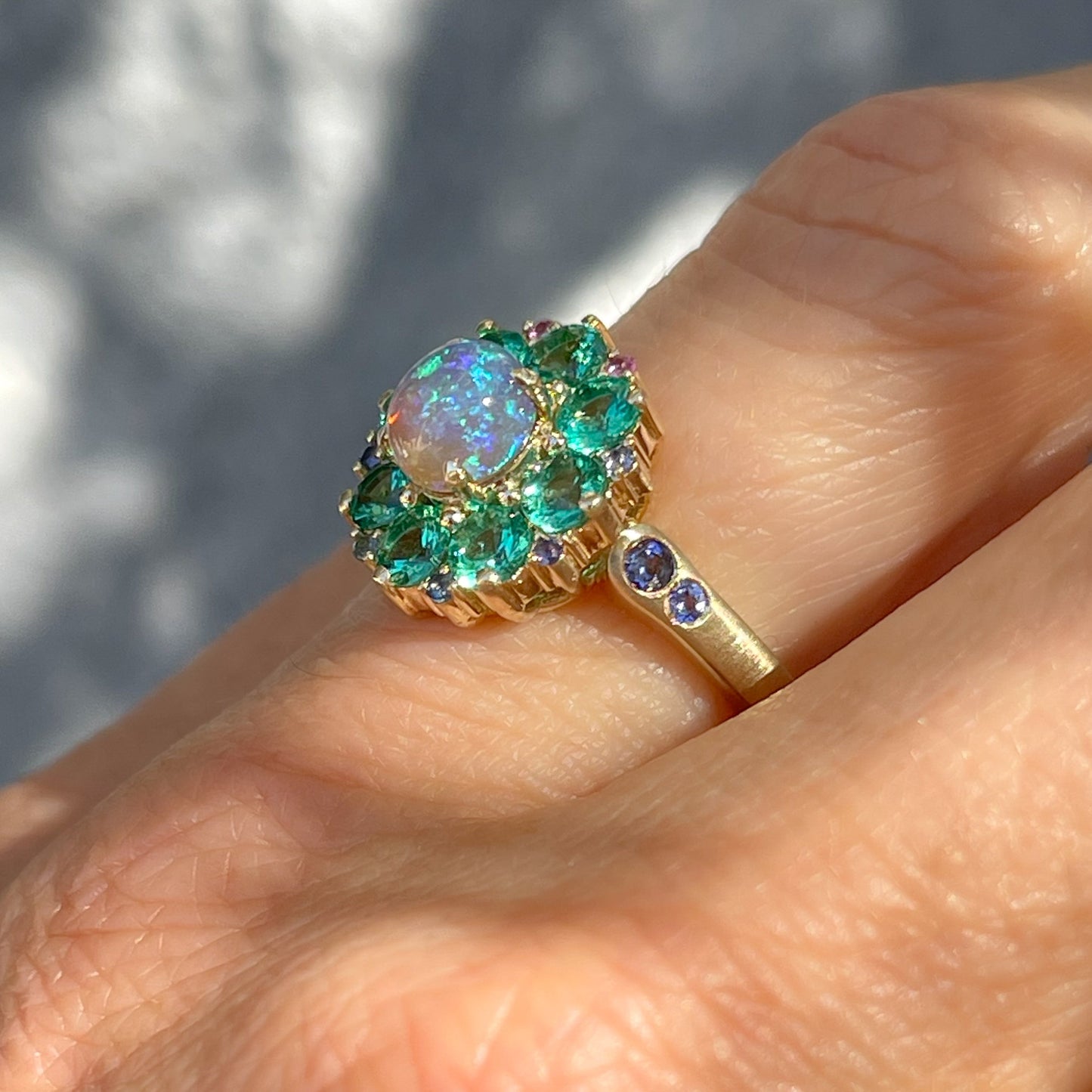 Profile view of an Australian Opal Ring by NIXIN Jewelry. An emerald and opal ring set in 14k gold.