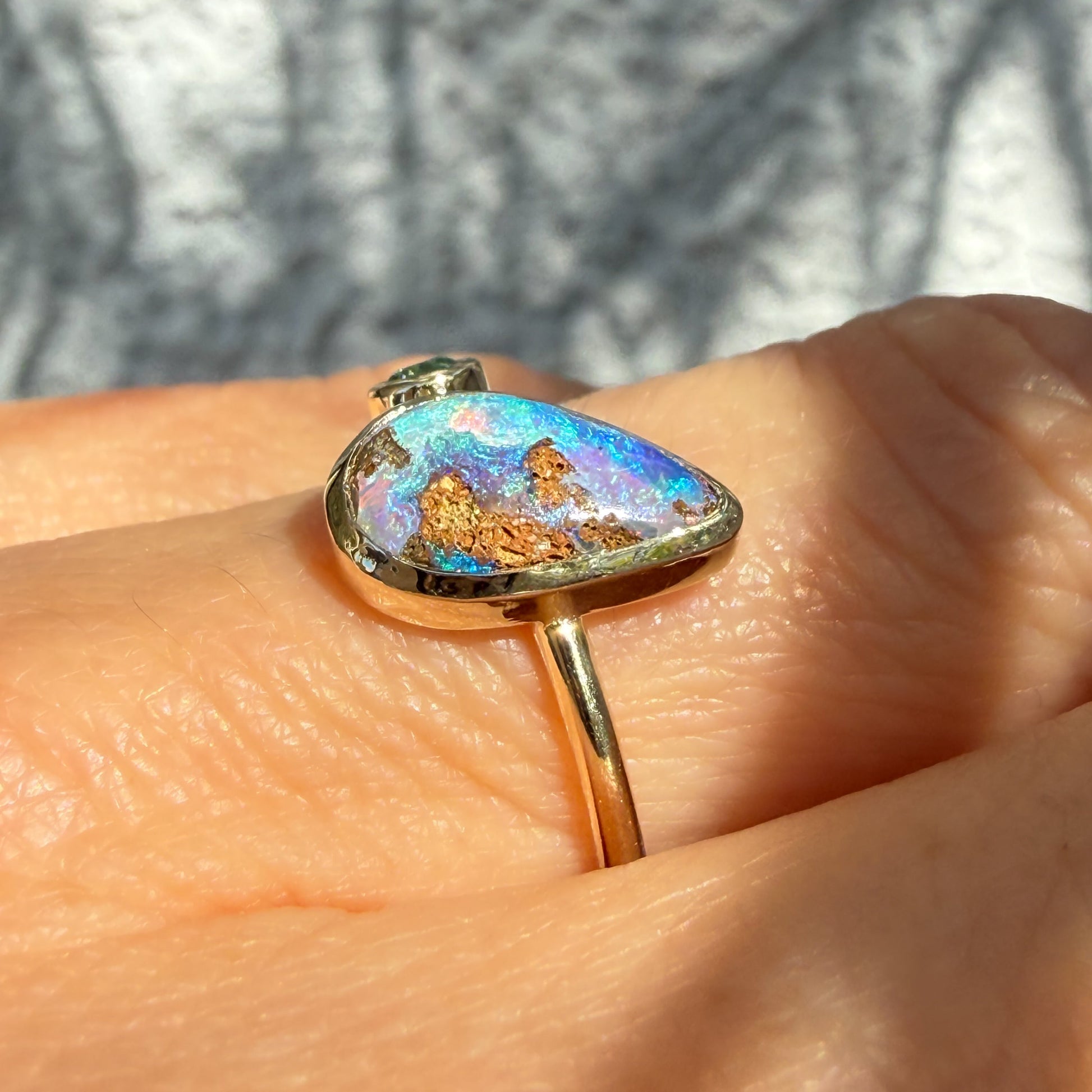 This is an Australian Opal Ring by NIXIN Jewelry showing the unique details of the stone. This macro photograph provides a close-up view of the natural opal in this emerald opal ring, focusing on the complex pattern of the matrix within the blue opal. This distinct pattern showcases the artistry found in rare jewelry and one-of-a-kind opal stones.