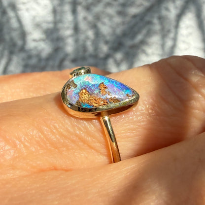 This is an Australian Opal Ring by NIXIN Jewelry showing the unique details of the stone. This macro photograph provides a close-up view of the natural opal in this emerald opal ring, focusing on the complex pattern of the matrix within the blue opal. This distinct pattern showcases the artistry found in rare jewelry and one-of-a-kind opal stones.