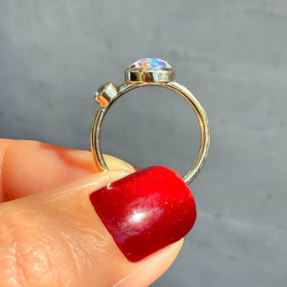 This profile photograph showcases an Australian Opal Ring by NIXIN Jewelry held to reveal the sleek architecture of the gold band. The image highlights the modern bezel setting of the emerald opal ring, emphasizing its low-profile and wearable design. This perspective provides an excellent view of the craftsmanship behind this piece of unique fine jewelry.