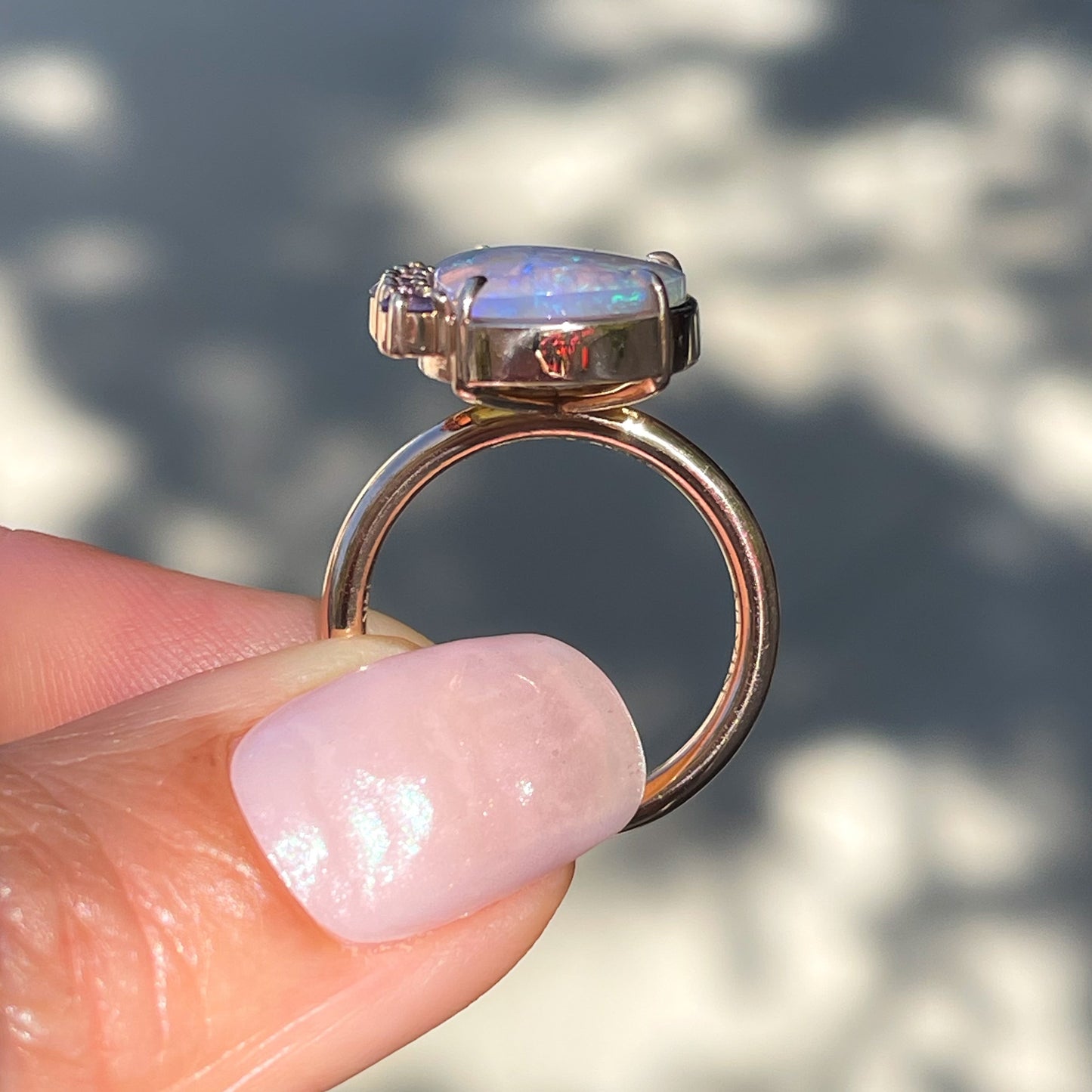 A profile shot of an Australian Opal Ring by NIXIN Jewelry. The opal ring sits low in profile with the opal and sapphires atop a full round band.