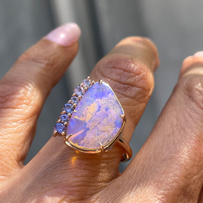An Australian Opal Ring by NIXIN Jewelry modeled on a hand in the shade. The natural opal ring is a true piece of jewelry art.
