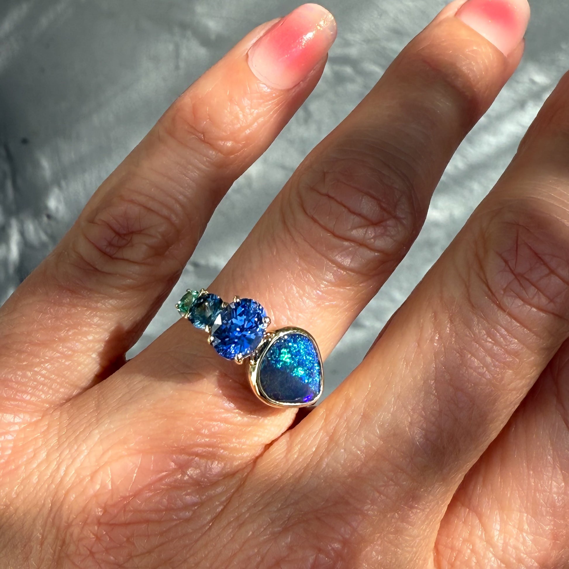 An Australian Opal Ring by NIXIN Jewelry. This black opal ring is a true jewelry art piece, worn on a hand, with the natural opal and the ombré sapphires creating a striking contrast.